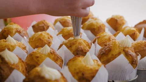Close-up view of female hands puts the cream from pastry bag on cupcakes. Stock Footage 108635409