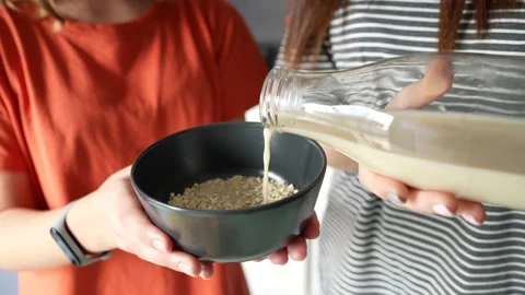 Close up view female hands putting oatmeal drink on a plate with rolled oats Video stock 167387196