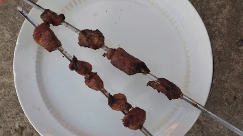 Close-up view. Female hands spread the barbecue on a skewer on a dish. Video stock 129316616