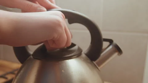 Close view of fingers lifting steaming kettle. Detailed scene capturing fingers Vidéo 346232965