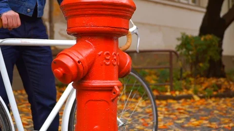 Close-up view of the fire hydrant and a man with a vintage bycicle on a Stock Footage 119772377