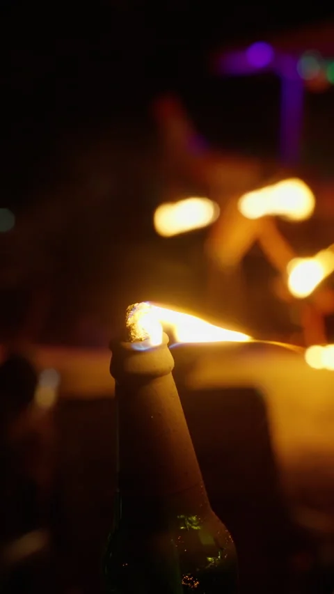 A close-up view of a flaming bottle during a dynamic fire performance at night Video stock 310491276