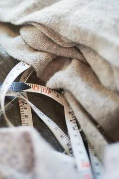 Close-up view of a flexible measuring tape wrapped around soft grey wool fabr Fotos de archivo