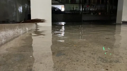 Close up view flooded cement ground at residential home at night. Video stock 256703128