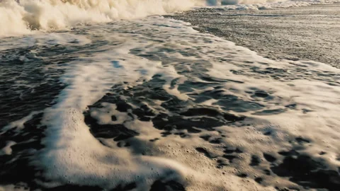 A close view to foamy see waves passing over beach sand Stock Footage 143436477