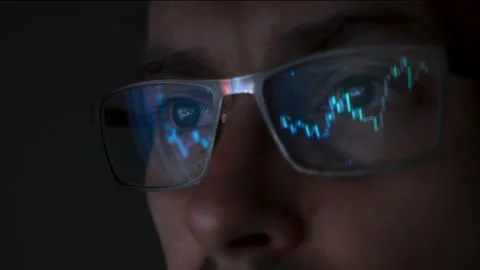 Close up view of focused trader wears eyeglasses looking at pc screen with stock Stock Footage 317614366