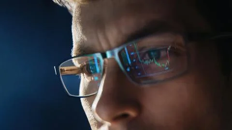 Close up view of focused trader wears eyeglasses looking at pc screen with stock Stock Photos