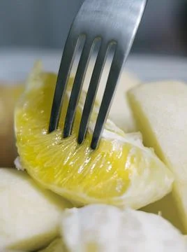 Close up view of fork picking up slice of orange Stock Photos