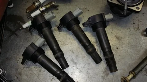Close-Up View of Four Ignition Coils and Spark Plugs on Workshop Floor Stock Footage 346411230