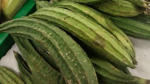 A Close-Up View of Fresh Angled Luffa Gourds at a Market Stall Stock Photos