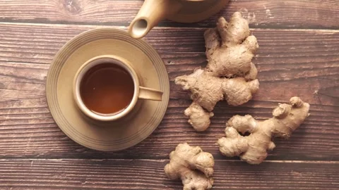 Close up view of fresh ginger roots and a cup of herbal tea on wooden backg.. Stock Footage 332626417