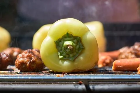 Close-up view of fresh green bell peppers grilling on a hot metal barbecue .. Stock Photos