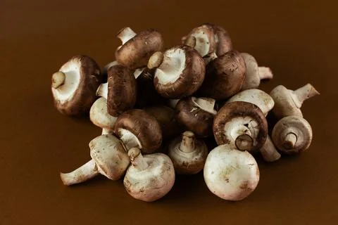 A Close-Up View of a Fresh Pile of Button Mushrooms on a Brown Background Foto stock