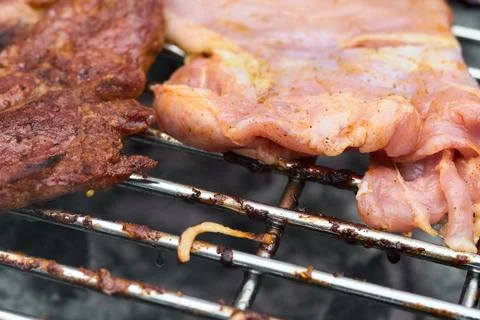 Close-up view of fresh raw meat and seasoned steak cooking on a hot grill gra Stock Photos