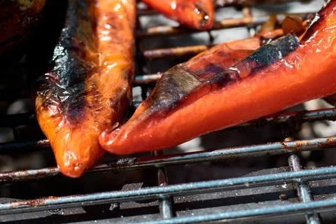 Close-up view of fresh red peppers roasting on a hot charcoal grill grate Stock Photos