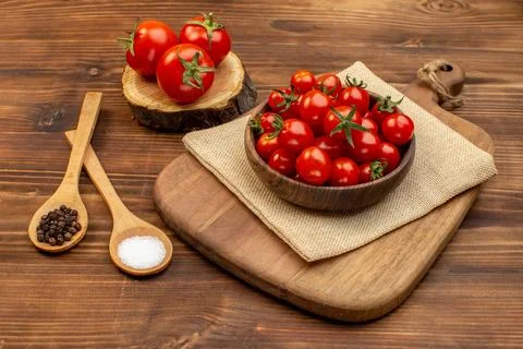 Close up view of fresh tomatoes on a brown bowl on cutting board on wooden .. Stock Photos
