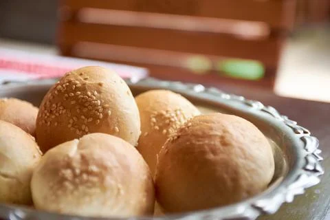 Close-up view of freshly baked bread rolls with sesame seeds in metal bowl Stock Photos
