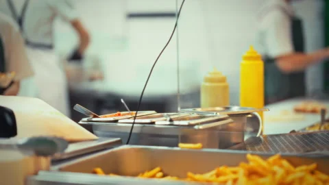 Close-up view of freshly cooked French fries prepared in a bustling industri Stock Footage 331348640