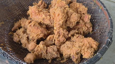 Close-up view of freshly fried crispy chicken pieces resting in a woven basket Vídeo Stock 325693897