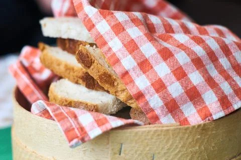 Close-up view of freshly sliced bread served in a round wooden basket wrapp.. 스톡 사진