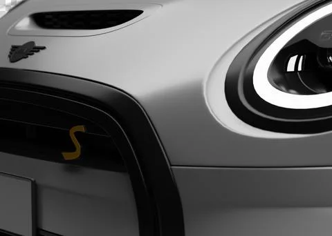 Close-up view of front headlight and red S logo on Mini Cooper SE Electric .. Stock Illustration