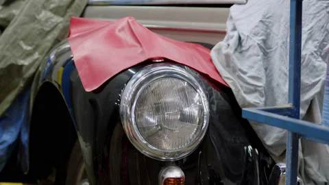 Close view of front headlight of retro car in black color in car service. Work Stock Footage 220908753