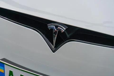 A close-up view of the front section of a Tesla vehicle displays its logo, .. Stock Photos