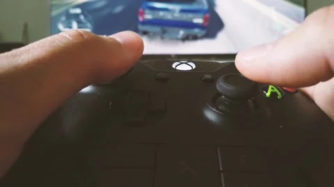 Close view of a gamer's hands playing racing video game on his xbox console Stock Footage 133259511