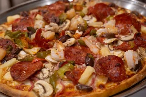 A close-up view of a generously topped pizza featuring pepperoni, shrimp, m.. Stock Photos