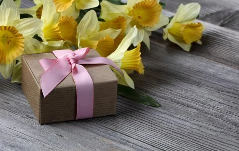 Close up view of a gift box with yellow daffodil on weathered wooden planks f Stock Photos