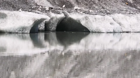 Close up view of glacial ice melting with droplets falling into water Stock Footage 332186596