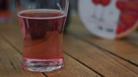 Close up view of a glass of cherry cider. People drinking alcohol in a bar.  Video stock 154871963
