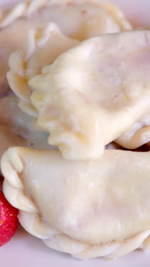 Close-up view of glossy dumplings on pale plate, folded crimped edges visible in Stock Footage 345161761