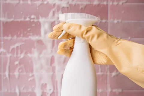 Close view of gloved hand holding a white cleaning spray bottle Foto stock