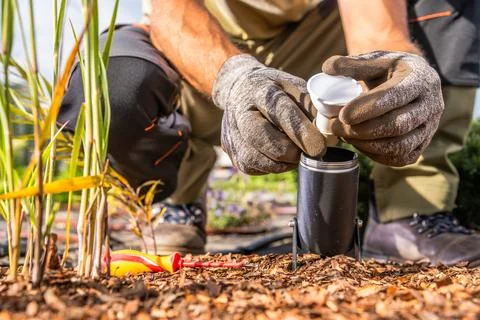 Close view of gloved hands fitting a light bulb into a ground mounted garden  Stock Photos