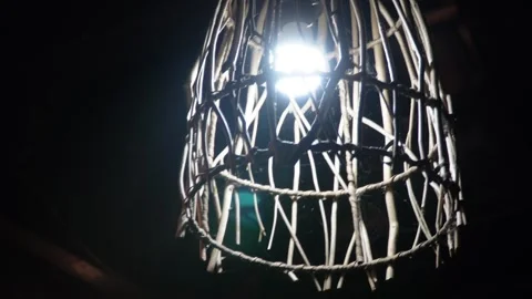 Close up view of a glowing bright electric light bulb inside a rustic wooden  Video stock 337870713
