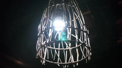 Close up view of a glowing bright electric light bulb inside a rustic wooden  Video stock 337870725