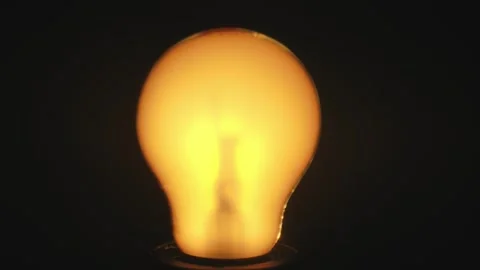 Close up View of a Glowing Light Bulb Against Dark Background Video stock 329765936