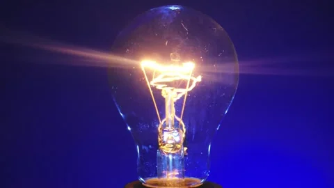 Close up View of Glowing Light Bulb on Blue Background Vídeos de archivo 329766476