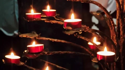 Close view of glowing red candles arranged on a wrought iron holder in darkness. Stock Footage 329256184