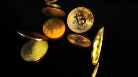 Close-up view, gold Bitcoin physical coin falls on glass black table. Stock Footage 266984016