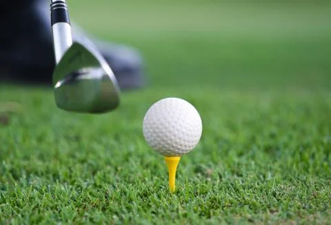 Close-up view of a golf ball set on a wooden golf tee in the grass with a gol Stock Photos