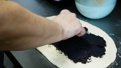 Close up view of granny�s hand smearing poppy seeds on a pastry via spoon Stock Footage 99360526