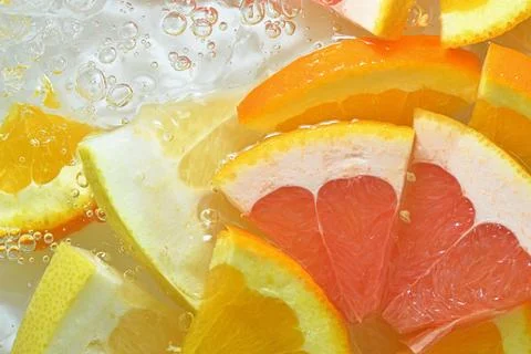 Close-up view of the grapefruit, orange fruit and honey pomelo slices in wa.. Stock-Fotos