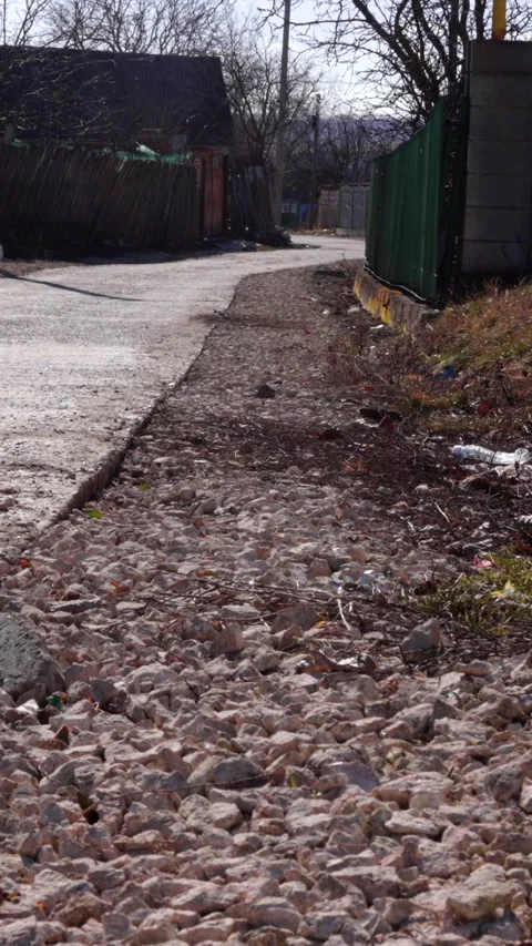 Close-up view of gravel pathway alongside a concrete road, with visible grass Stock Footage 338398098