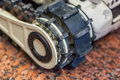 Close-up view of a gray and white robotic device on an uneven, speckled surfa Stock Photos