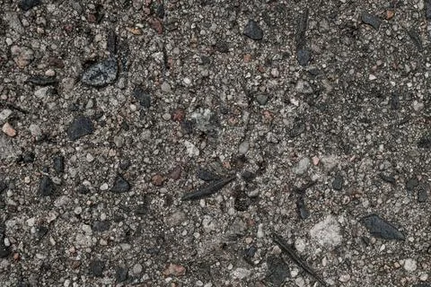 Close-up view of gray asphalt surface with colorful stones. Stock Photos