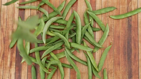 Close view of green beans falling over wooden background Stock Footage 159638011