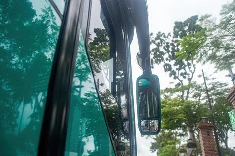 A close up view of a green bus side mirror reflecting trees and a brick str.. Stock Photos