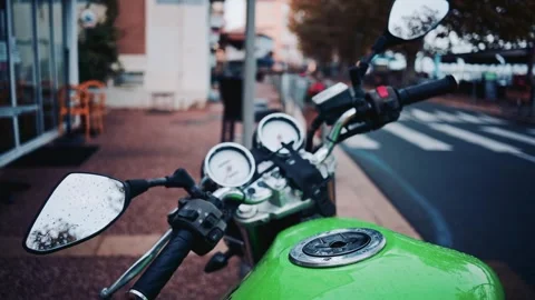 A close-up view of green motorcycle on sidewalk with city street background.. Vidéo 339751927